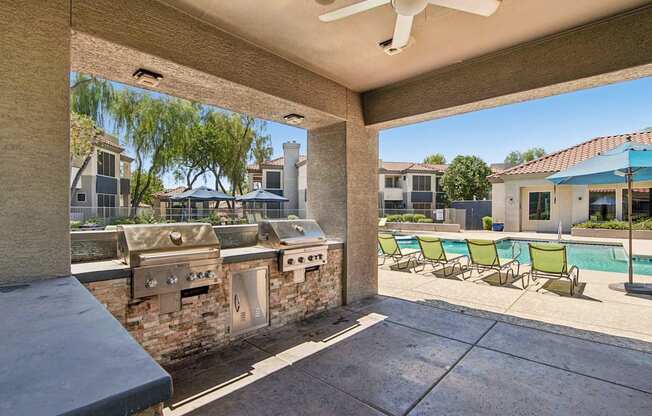 A patio with a pool and a grill.