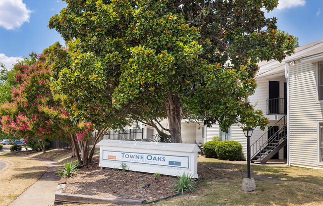 A sign that says Towne Oaks is in front of a tree.