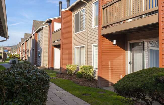 Exterior view of orange and tan apartments with balconies and patios at Pointe East in Fife, WA.