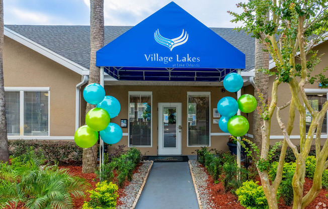 the front entrance to village lakes apartments with balloons and a blue roof