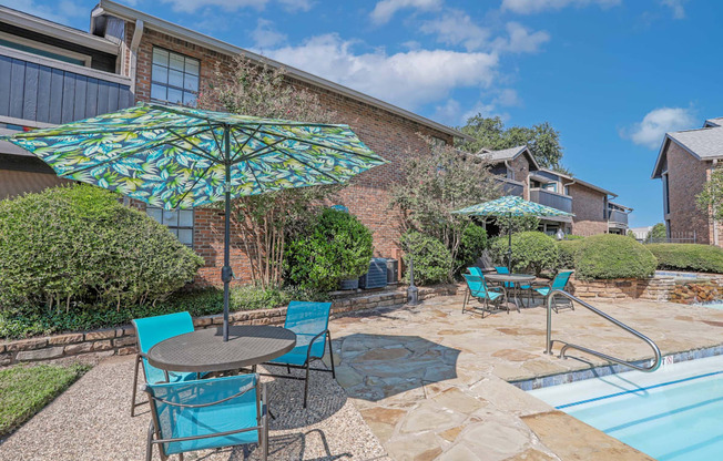Poolside seating with shaded tables and chairs at The Pearl apartments in Shreveport, LA