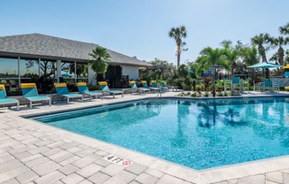 a resort style pool with lounge chairs and umbrellas