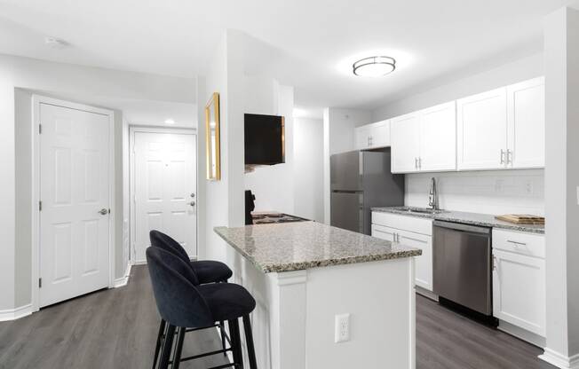 a kitchen with an island and a counter top with black chairs