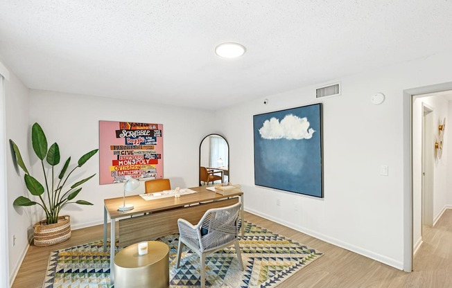 A room with a desk, chair, and a potted plant.