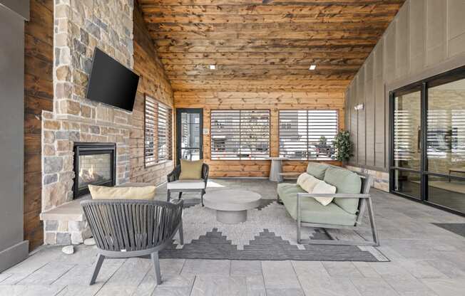 an outdoor living room with a stone fireplace and a tv