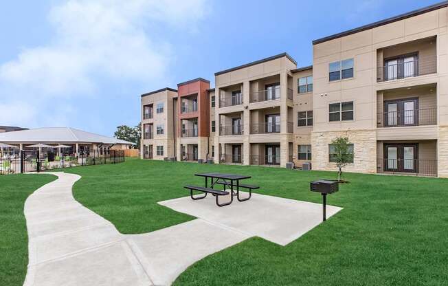 Apartment complex with a grassy area and picnic table.