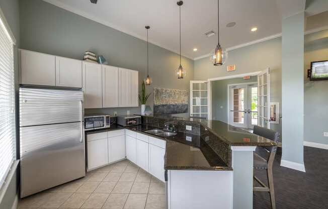 a kitchen with white cabinets and granite counter tops and a stainless steel refrigerator