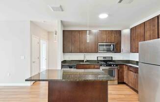 a kitchen with dark wood cabinets and an island with granite countertops at West 130, New York