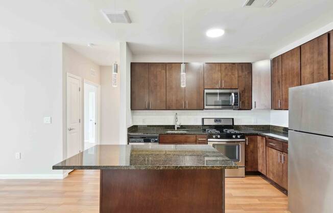 a kitchen with dark wood cabinets and an island with granite countertops at West 130, New York