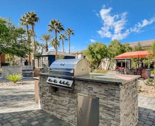 A stone outdoor kitchen with a grill and a sink.