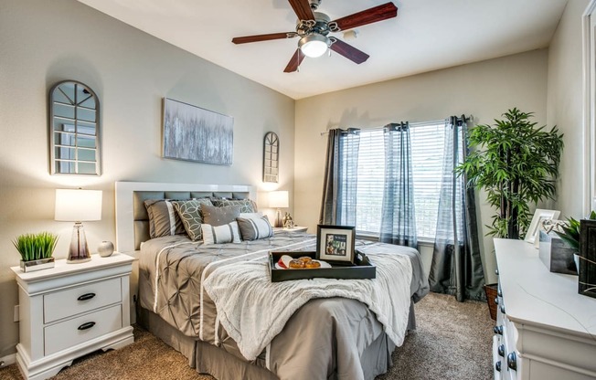 Apartment Houston, TX - Spacious Bedroom with Plush Carpet, a Large Window, and a Ceiling Fan