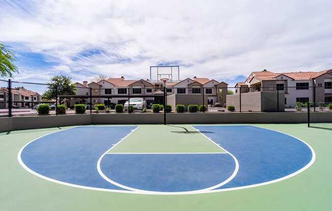 an outdoor basketball court with houses in the background