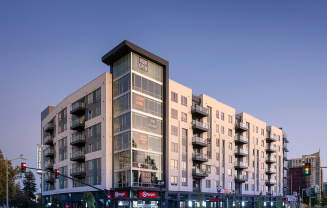 Exterior of the mid-rise Hanover Broadway building located on a street corner, with balconies on each level and a Target on the bottom floor.