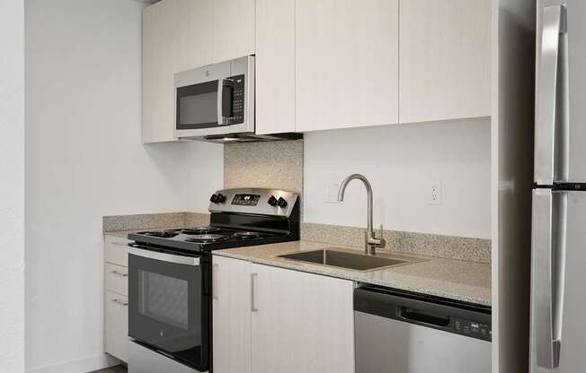 A kitchen with a stove, microwave, and refrigerator.