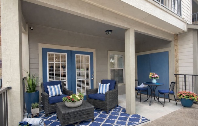 A patio with blue and white furniture and a blue rug.