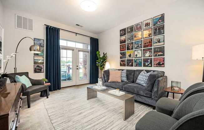 A living room with a grey couch, a coffee table, and a wall with pictures.