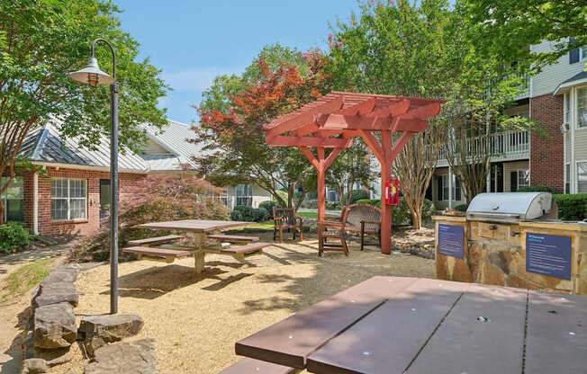 A sunny day at the park with picnic tables and a grill.