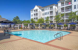 a swimming pool at an apartment complex with umbrellas