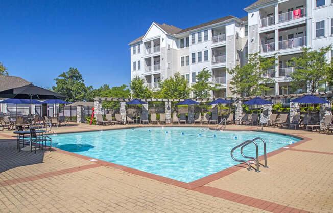 a swimming pool at an apartment complex with umbrellas