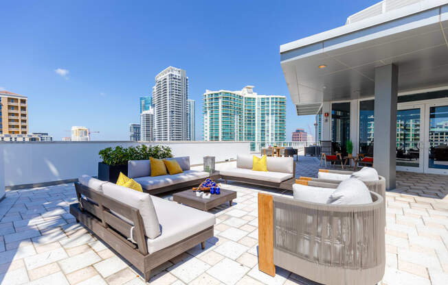 a terrace with couches and chairs and a city in the background