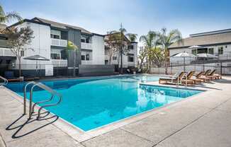 A swimming pool with a blue tinted water and sun loungers at Verandas Apartments, West Covina, 91791