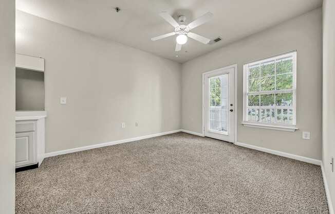 an empty living room with a ceiling fan and a window
