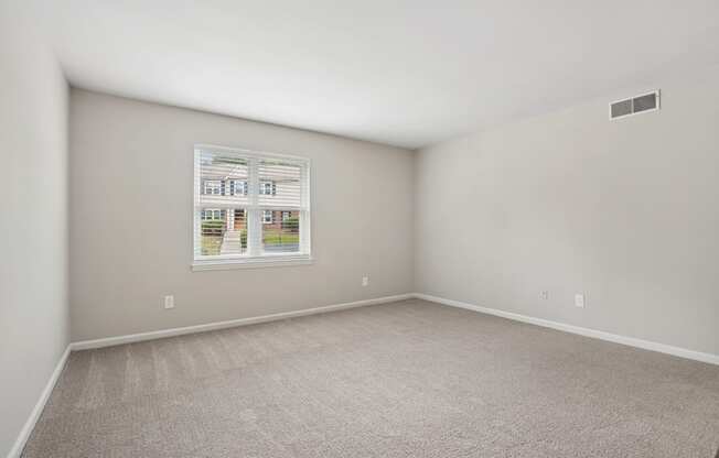 A room with a carpeted floor and a window showing a view of a building.