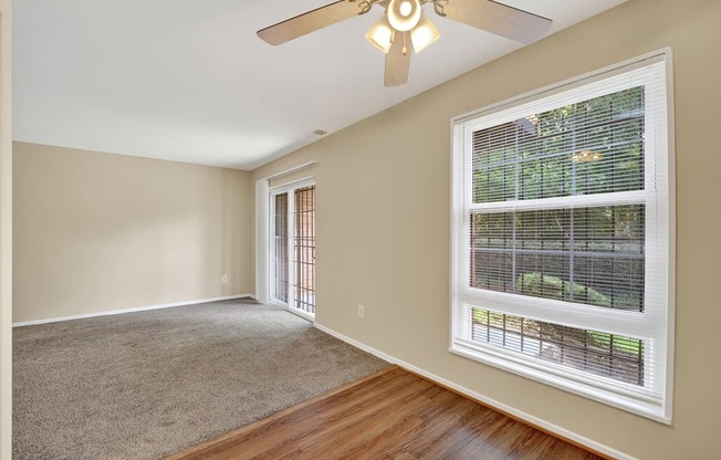 A room with a ceiling fan and a window with blinds.
