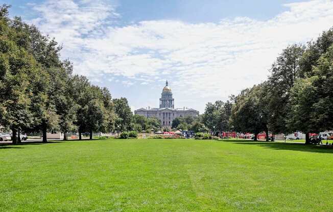 A large grassy field with trees and a building in the background.