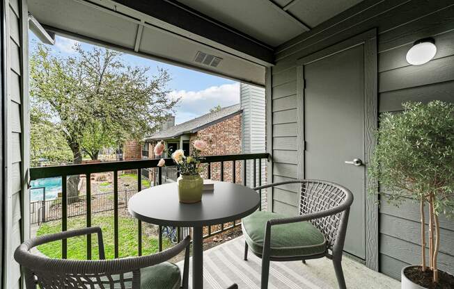 a patio with chairs and a table on a balcony at Legacy Apartments in Plano, TX