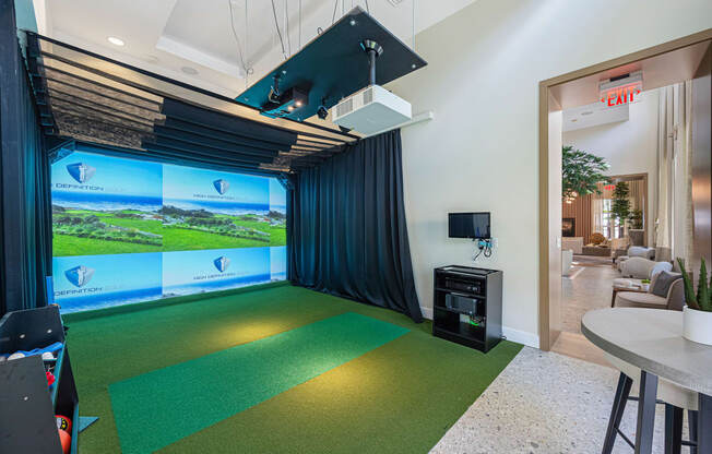 a game room with a golf simulator and a green carpet