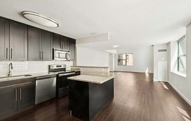 A modern kitchen with dark wood floors and stainless steel appliances.