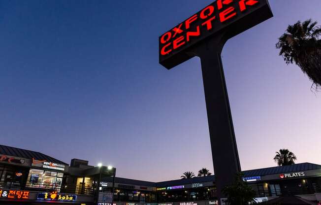 a large illuminated sign in front of a shopping center at night