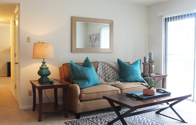 A living room with a couch, a table, and a mirror.