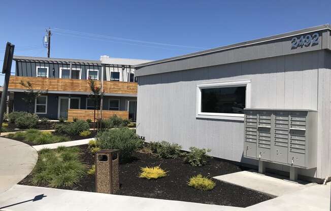 a gray building with a wooden building in the background