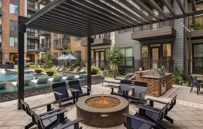 A patio with a fire pit and chairs.