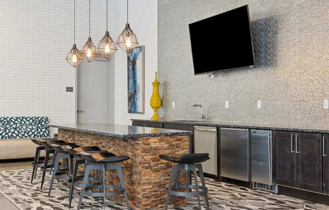 A modern bar area with a stone counter and stools.