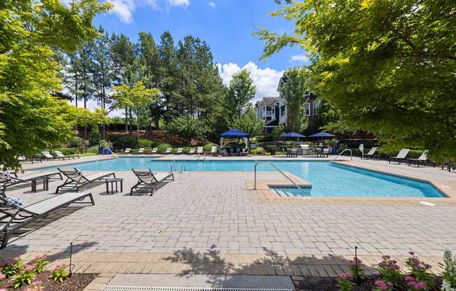 a swimming pool with lounge chairs and trees surrounding