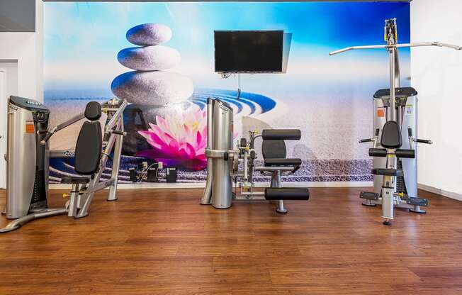 a room filled with cardio equipment and a wall mural of a pink flower