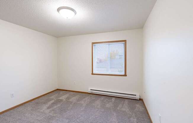 an empty living room with carpet and a window. Fargo, ND Oxford Apartments