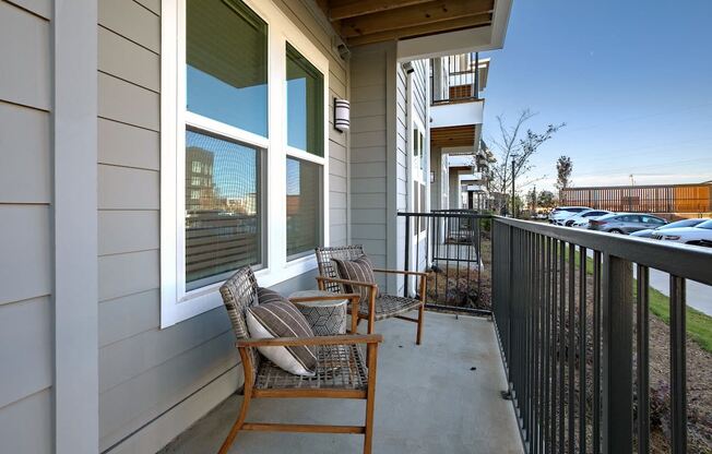 a view of a balcony with tables and chairs and a building in the background