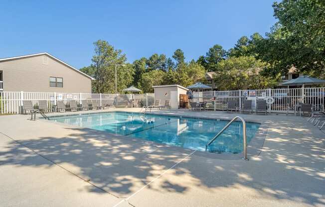our resort style pool is surrounded by a fence and trees