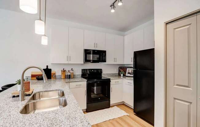 A kitchen with black appliances and white cabinets.