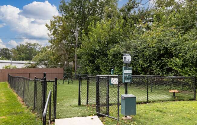 a chain link fence surrounds a park with a tennis court