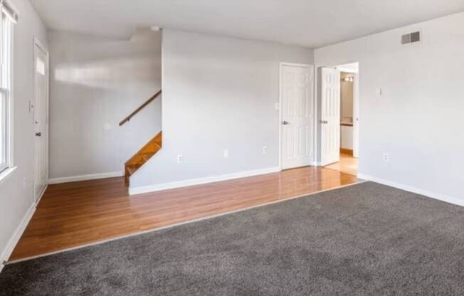 A room with a grey carpet and wooden floors.