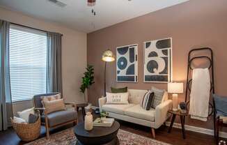 A living room with a white couch, a grey armchair, a coffee table, and a plant.