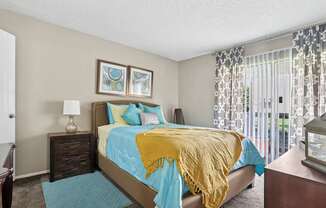 A bedroom with a bed covered in a blue and yellow comforter.