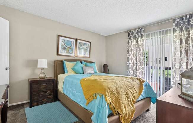 A bedroom with a bed covered in a blue and yellow comforter.