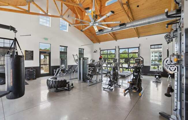 A gym with a variety of equipment including a punching bag, treadmills, and weights.