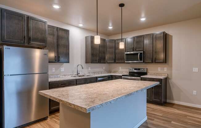 a kitchen with stainless steel appliances and a marble counter top. Fargo, ND Prairiewood Meadows Apartments